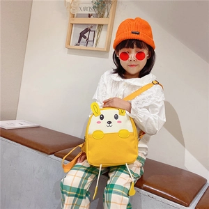 Toddler wearing a yellow rabbit canvas backpack with ears in a cozy indoor setting