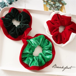 Three-piece velvet Christmas scrunchies in festive red and green on a white tray