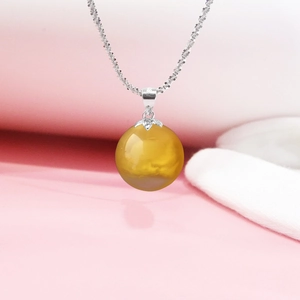 Macro shot of silver pearl pendant bail with a spherical amber stone and elegant chain