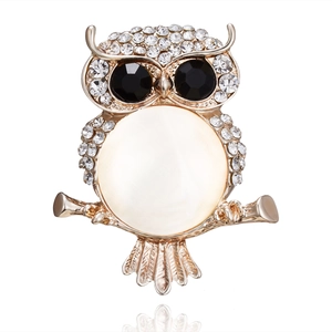 Macro shot of owl brooch with white crystals, black gem eyes and white opal belly