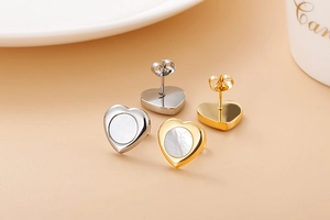Macro detail of heart-shaped titanium steel earrings with shell inlay in gold and silver