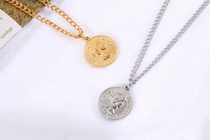 Dettaglio dei ciondoli a moneta d'oro e d'argento con rilievo di Elisabetta II e catenina