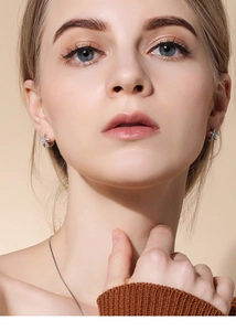 Close-up of small silver star earrings with sparkling texture worn on a female model