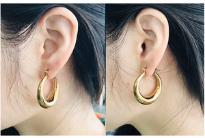 Close-up of chunky gold teardrop hoop earrings featuring a polished 18K finish