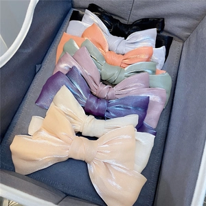 Close-up of assorted satin bow hair clips in various colors organized in a grey storage box