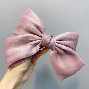 Detailed view of shimmering pearlescent organza bow hair clip in elegant dusty pink