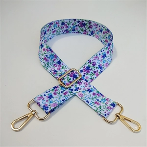 Detail of adjustable floral wide bag strap with blue blossoms and gold swivel hooks