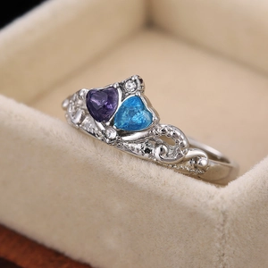 Elegant alloy crown ring with blue and purple heart-shaped zircons on a beige velvet box