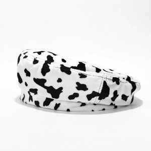 Détail du tissu en peluche doux et du motif de vache noir et blanc sur le béret