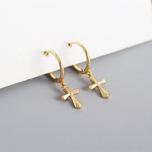 Macro shot of minimalist gold S925 sterling silver hoop earrings with cross pendants