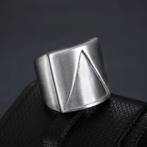 Close-up of geometric wide stainless steel ring with triangular matte textured engraving