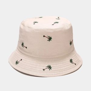 Detail of beige cotton bucket hat featuring intricate coconut tree embroidery patterns