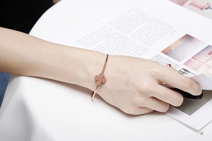 Close-up of rose gold clover bracelet on wrist against a clean white lifestyle background