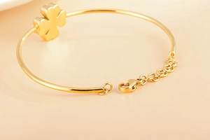 Detailed macro of gold four-leaf clover bracelet with adjustable lobster clasp and extension