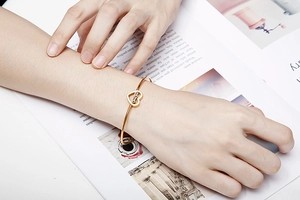 Detailed view of an adjustable gold heart bracelet with 'Mama' lettering on model's wrist
