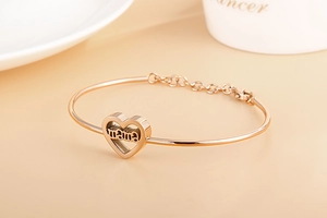 Detail of rose gold heart bracelet with MAMA engraving on a warm elegant background