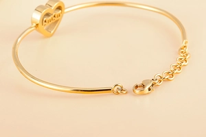 Detail of adjustable gold heart bracelet with MAMA engraving and lobster clasp closure