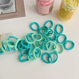 Close-up of blue and mint green fabric hair ties scattered on a white table