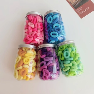 Detail view of five jars containing colorful soft seamless fabric hair ties in pastel tones