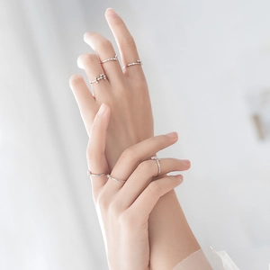Close-up of minimalist silver rings set with zircon accents worn on fingers