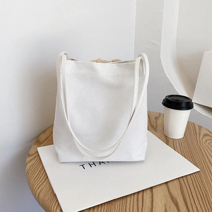 Sac fourre-tout minimaliste en toile blanche avec breloque ours en peluche sur table