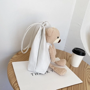Sac fourre-tout en toile blanche avec petit ours en peluche sur table en bois