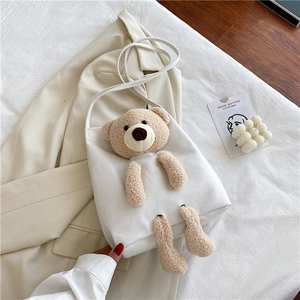 Vue détaillée du sac en toile blanc avec ours en peluche marron sur tissu beige