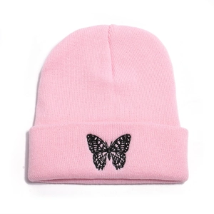 Close-up of pink knitted beanie with detailed black butterfly embroidery on the cuff