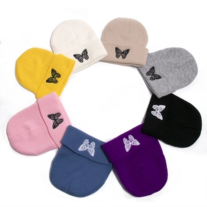 Close-up of assorted colorful knitted beanies with delicate butterfly embroidery details