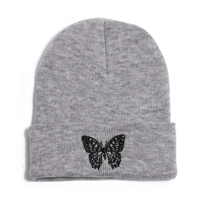Close-up of a grey knitted beanie featuring a detailed black butterfly embroidery