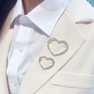 Close-up of heart-shaped brooch set with sparkling rhinestones on beige suit jacket