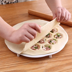White 19-hole plastic dumpling maker mold for quick batch prep on a wood table