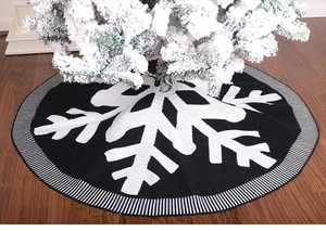 Detail of black and white knitted Christmas tree skirt with snowflake pattern and stripes