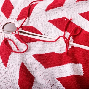 Red and white knitted Christmas tree skirt with snowflake patterns and tie closure