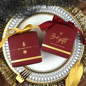 Burgundy wedding candy boxes with gold foil text and decorative ribbon bows detail