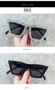 Macro detail showing crystal rhinestones on the oversized black cat-eye sunglasses frame