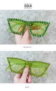 Detail view of oversized green rhinestone sunglasses with polished frame and crystals