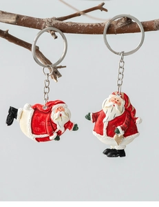 Detail of two festive Santa Claus keychains with red suits hanging on a branch