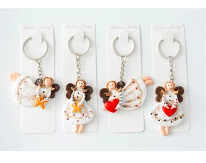 Detail view of four angel Christmas keychains with red hearts and golden stars on cards