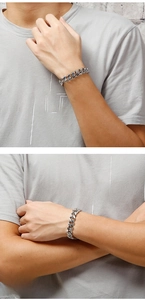Close-up of men's silver stainless steel Cuban link bracelet worn on a wrist in street style