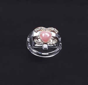 Dettaglio anello oro rosa con cuore rosa e zirconi bianchi su supporto espositore