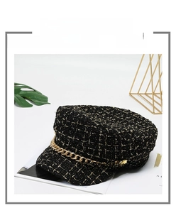 Close-up of black tweed beret hat featuring a stylish gold metal chain decoration