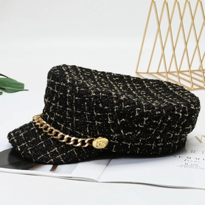 Elegant black tweed navy hat with golden chain detail and metallic badge on white background