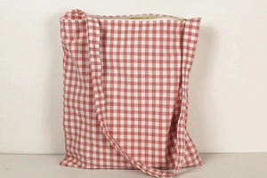 Detail of red and white gingham canvas tote bag with top zipper and long shoulder strap