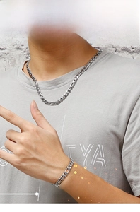Close-up of stylish silver Figaro chain necklace and bracelet set on male model