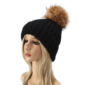 Detalle de gorro de punto negro con un pompón de piel real de mapache muy esponjoso