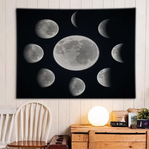 Black moon phase tapestry hanging on white wall in cozy minimalist room setting