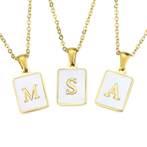 Macro detail of gold square pendants with M, S, A letters on white shell inlay