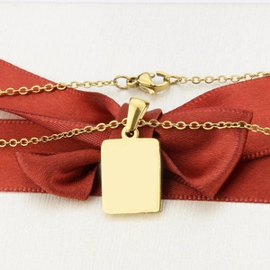 Close-up of golden rectangular pendant necklace on a red silk bow for gift display