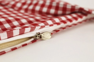 Macro view of white zipper detail on red and white gingham cotton canvas bag